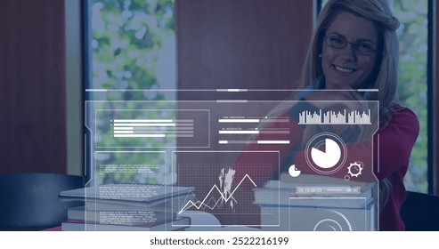 Image of charts processing over happy caucasian female student at desk with books. Learning, education, data, digital interface and communication, digitally generated image. - Powered by Shutterstock