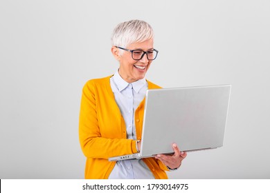 Image Of Cheerful Mature Woman Standing Isolated Over Gray Background Using Laptop Computer. Portrait Of A Smiling Senior Lady Holding Laptop Computer