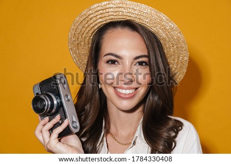 Image of cheerful nice woman using retro camera and smiling isolated over yellow background