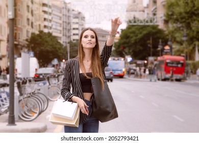 Image In The City Center. Girl With Bags Signals To A Bus Driver