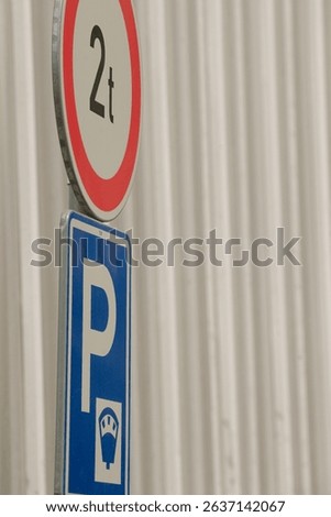 The image clearly shows a prominently displayed parking sign that indicates a maximum weight limit of 2 tons, situated next to a recognizable blue parking symbol for visual guidance