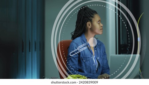 Image of clock moving over biracial woman working in servers room. network, programming, computers and technology concept digitally generated image.