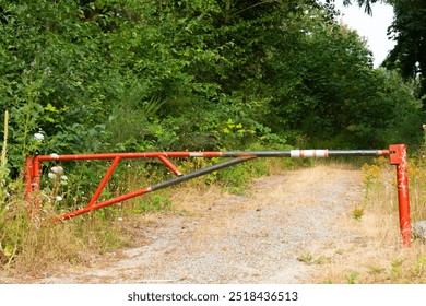 An image of a closed red metal gate restricting access to a rural road.  - Powered by Shutterstock