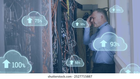 Image of clouds with increasing numbers over stressed caucasian man standing at servers. cloud computing, data uploading, computers and technology concept digitally generated image.