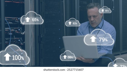 Image of clouds with numbers over stressed caucasian man working on laptop in server room. cloud computing, data uploading, computers and technology concept digitally generated image. - Powered by Shutterstock