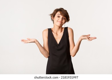 Image Of Clueless Girl In Black Dress Shrugging, Looking Confused, Standing Over White Background