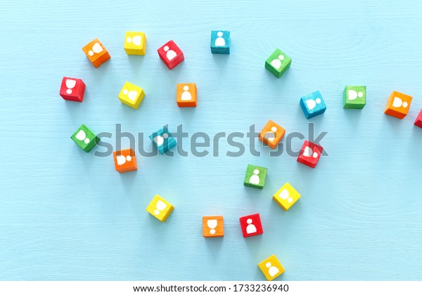 image of colorful blocks\
with people icons over wooden table ,human resources and management\
concept