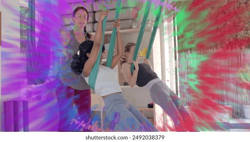 Image of colourful trails over diverse female instructor and teenage girls doing aerial yoga. Wellbeing, energy, fitness, connection and healthy lifestyle, digitally generated image. - Powered by Shutterstock