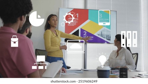 Image of communication media icons over diverse colleagues at presentation in casual office. Connection, data, processing, network, digital interface and communication, digitally generated image.