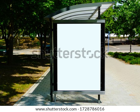 image composite of bus shelter at bus stop of blank light box and glass structure. park-like urban setting. green background. safety glass design. white poster ad commercial poster space display glass