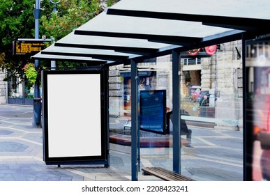 Image Composite Of Bus Shelter. Bus Transit Stop. Blank White Lightbox. Glass Structure. Urban Setting. City Street Background. Stone Sidewalk. Empty Poster Ad Commercial Space. Background For Mockup