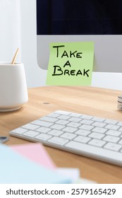An image of a computer screen on a desk with a sticky note that reads 