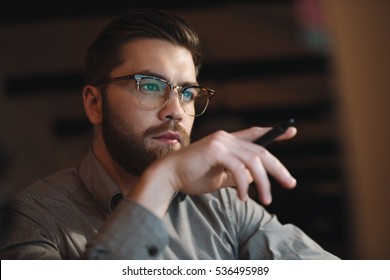 Image Of Concentrated Bearded Web Designer Dressed In Shirt Working Late At Night And Looking At Computer. Holding Pen.