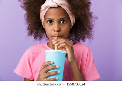 Image Of A Concentrated Young African Girl Kid Posing Isolated Over Purple Wall Background Drinking Soda.