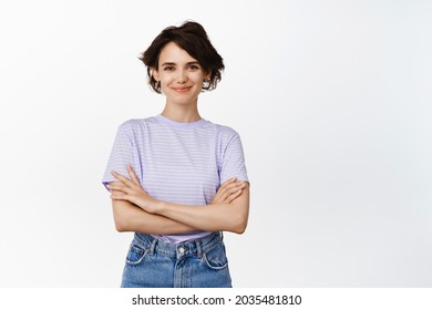 Image of confident brunette female model, girl looks assertive and ready, cross arms on chest like professional, smiling smug face, standing over white background.