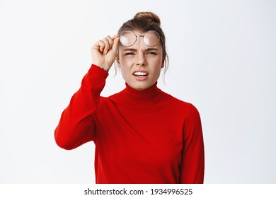 Image Of Confused Blond Girl Take-off Glasses And Squinting, Trying To See Something Without Eyewear, Standing Puzzled Against White Background