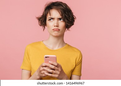 Image Of A Confused Young Beautiful Woman Posing Isolated Over Pink Wall Background Using Mobile Phone.