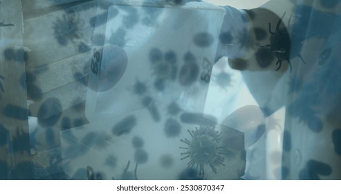 Image of coronavirus cells flowing over a male laboratory worker wearing protective gloves, examining samples. Covid 19 pandemic health care science medicine concept digital composite. - Powered by Shutterstock