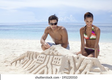 The Image Of Couple Building Sand Castles At The  Beach 