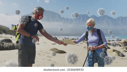 Image of covid 19 cells floating over senior couple wearing face masks with backpacks on beach. global coronavirus covid 19 pandemic concept digitally generated image. - Powered by Shutterstock