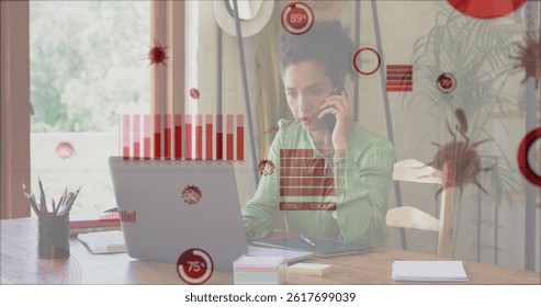 Image of covid 19 cells and statistics over biracial businesswoman using phone and laptop. Global covid 19 pandemic, business, finance and data processing concept digitally generated image.