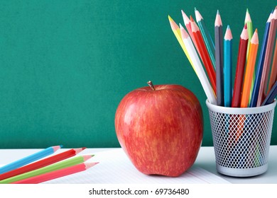 Image crayons   red apple against blackboard