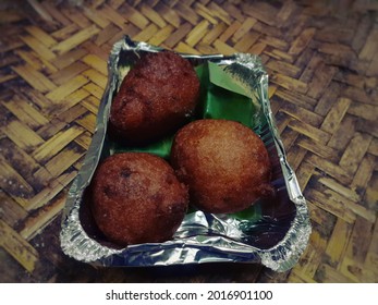 Image Of Crispy Brown Bonda In A Tin Foil Box, South Indian Takeaway Parcel Served With A Banana Leaf Inside, Like Mini Donut Closeup - Image, A Traditional And Popular Snack, Made From Deep Frying