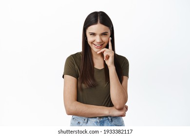 Image of cunning thoughtful woman giggle and squint at camera while looking mysteriously, have idea, make-up a plan, standing devious against white background