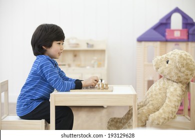the image of cute Asian kid playing chess with teddy bear