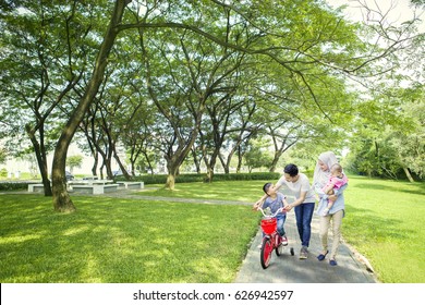 Image of cute boy learns to ride a bike with his family while walking together in the park - Powered by Shutterstock