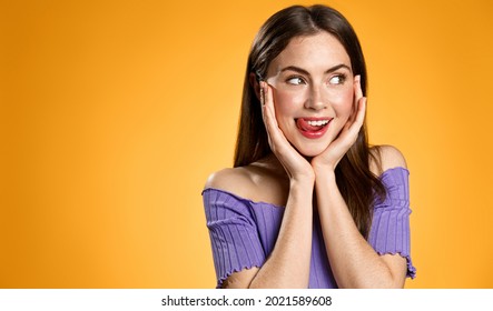 Image Of Cute Brunette Woman Smiling, Licking Lips From Desire To Taste Or Try Something Delicious, Gazing At Food, Standing Against Orange Background