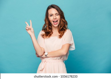 Image of cute young lady standing isolated over blue background. Looking camera showing peace gesture. - Powered by Shutterstock