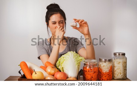 Image of the cuteness of young asian woman prepares the ingredients for kimchi with white garlic as a food ingredient. She feels the pungent smell of her nose.