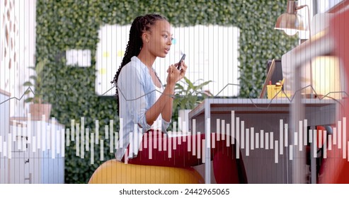 Image of data processing and diagram over biracial businesswoman talking on smartphone in office. Global business, technology and digital interface concept digitally generated image.