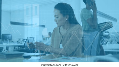 Image of data processing and digital icons over asian woman taking notes at office. Computer interface and business data technology concept - Powered by Shutterstock