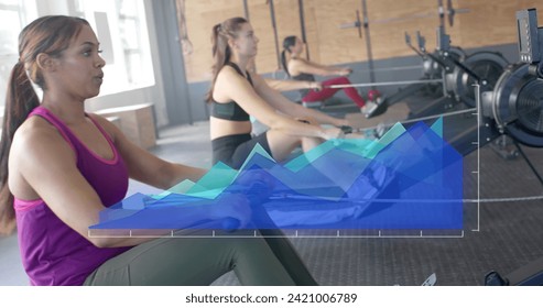 Image of data processing on blue graph over diverse women training on rowing machines at gym. Fitness, exercise, strength, data, digital interface and technology digitally generated image.