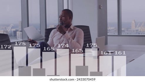 Image of data processing over african american businessman in office. Global business and digital interface concept digitally generated image.