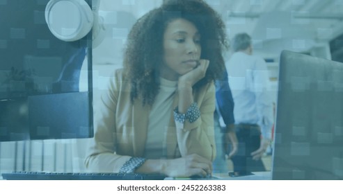 Image of data processing over african american businesswoman using laptop at office. Global business, finances and digital interface concept digitally generated image.