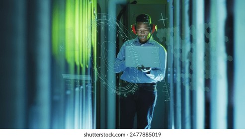 Image of data processing over african american male worker with laptop in server room. Global business, security and digital interface concept digitally generated image.