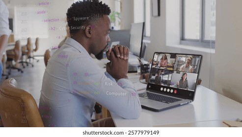 Image of data processing over african american man having laptop image call at office. Network, data, digital interface, business, teamwork and communication, digitally generated image.