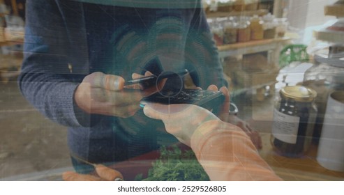 Image of data processing over biracial man paying with smartphone. Technology, communication, computing and digital interface concept digitally generated image.