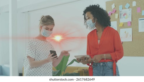 Image of data processing over businesswomen wearing face masks. global networks, business and connections during covid 19 pandemic concept digitally generated image.