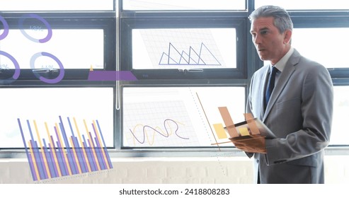 Image of data processing over caucasian businessman in office. Global finance, business, connections, computing and data processing concept digitally generated image.