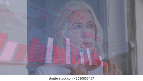 Image of data processing over caucasian woman with face mask. spending time at home during covid 19 pandemic concept digitally generated image.