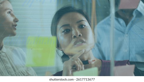 Image of data processing over diverse business people taking notes on glass wall. global business and digital interface concept digitally generated image.