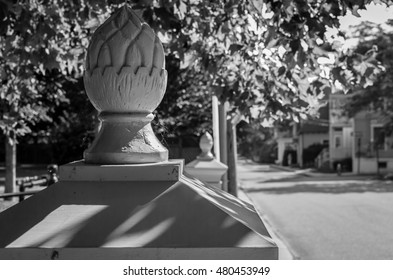 A Image Of A Decorative Fence Post Cap. An Artistic Fence Wall Post. Natural Sunlight And Shadow On An Suburban Street.