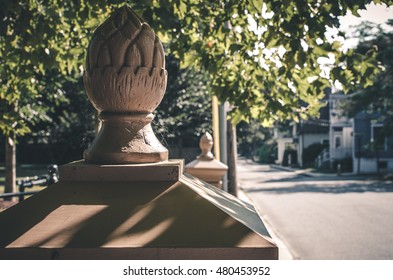 A Image Of A Decorative Fence Post Cap. An Artistic Fence Wall Post. Natural Sunlight And Shadow On An Suburban Street.