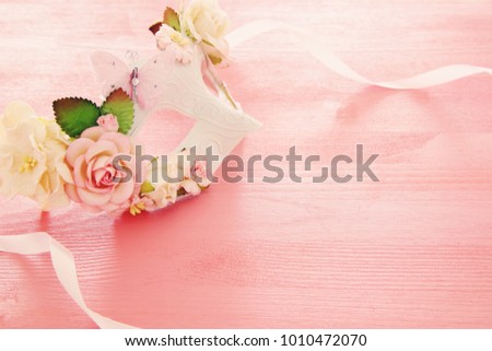 Image of delicate elegant venetian mask over wooden pink background. Selective focus