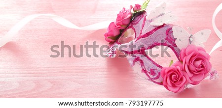 Image of delicate elegant venetian mask over wooden pink background. Selective focus