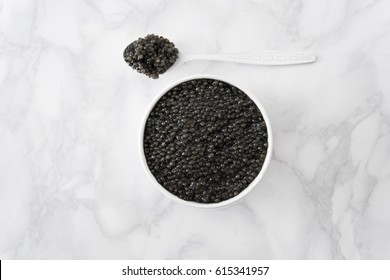 image of delicious black caviar in white bowl on marble table. flat lay